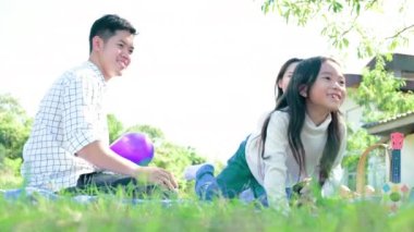 Genç aile parkta oturuyor ve balonlarla oynuyorlar.