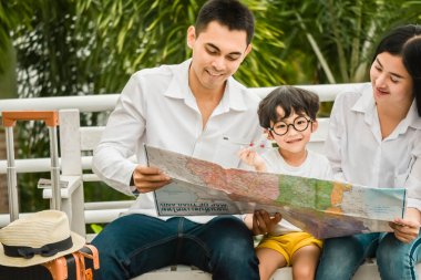 father mother and the son asian hold passport, map to trip family Preparing for traveling We are Poses selfie Before travel for vlog trip travel abroad lifestyle happy life with family. clipart
