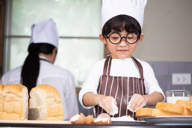Asyalı anne ve oğlu beyaz un pişiriyor ekmek hamuru eğitiyor anne çocuklara ekmek pişirmeyi, sofra takımında yumurta pişirmeyi öğretiyor.