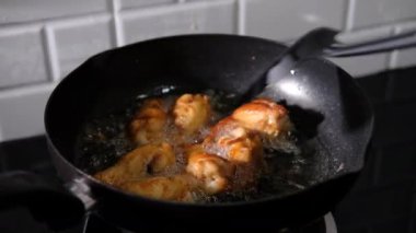 Asyalı bir adam mutfağında kızarmış tavuk pişiriyor. Elinde spatula ve tava var. Tayland yemeğiyle kızaran gaz sobasıyla. 