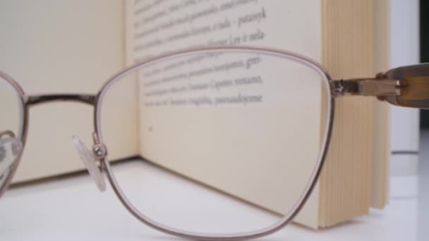 本にメガネを通してマクロビュー。読むことへの中毒。読書中に眠りに落ちる. — ストック動画