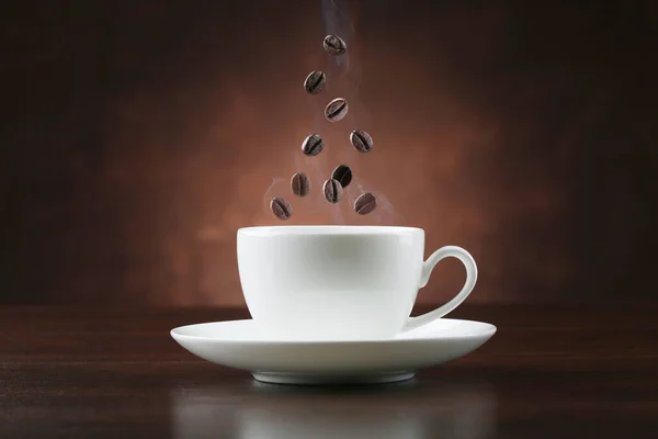 Cup Coffee Falling Beans Brown Background Closeup — Stock Photo, Image