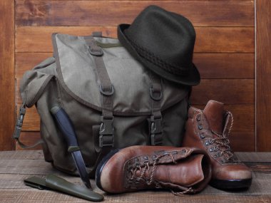 Eski çizme, bıçak ve ahşap zemin üzerine şapka ile sırt çantası
