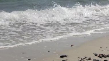 Dalga köpüğü plaj kumlu doku üzerinde bir Sandy Beach köpüklü dalgalar rulo üzerinde.