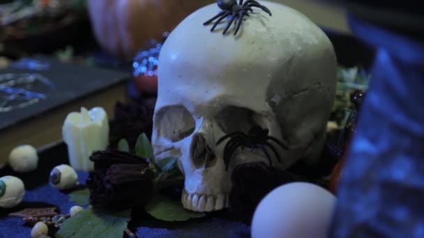 クローズアップ 人間の頭蓋骨からペンタグラムで黒い本への焦点の変化 カメラの滑らかな動き ハロウィン前夜の儀式のための魔女のテーブルの概念 — ストック動画