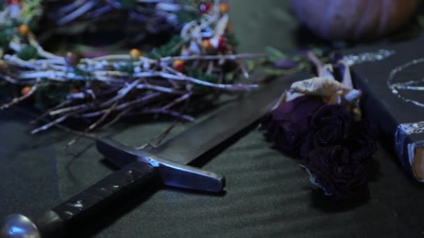 平稳的相机运动和焦点变化 桌子上有一把匕首的特写和一本有五芒星的黑色书 在万圣节前夕举行宗教仪式的女巫餐桌的概念 — 图库视频影像