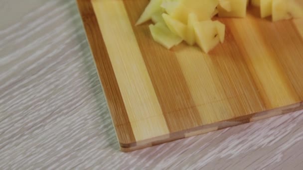 小さな立方体に刻んだジャガイモのクローズアップは まな板の上にあります — ストック動画