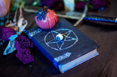 Kapağında pentagram olan siyah bir defter masanın üzerinde duruyor. Cadılar Bayramı için sihirli bir ayin düzenlemek için sunak konsepti..