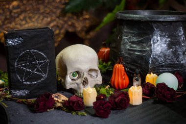 Masada pentagram, kafatası ve kazan bulunan kara kaplı bir defter ve cadılık malzemeleri. Cadılar Bayramı cadı sunağı kavramı.