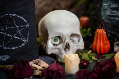 Masada pentagram, kafatası ve kazan bulunan kara kaplı bir defter ve cadılık malzemeleri. Cadılar Bayramı cadı sunağı kavramı.