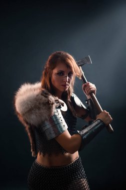 Karanlıkta elinde baltayla ortaçağdan kalma fantezi Viking kadın portresi. Dişi savaşçı silueti.
