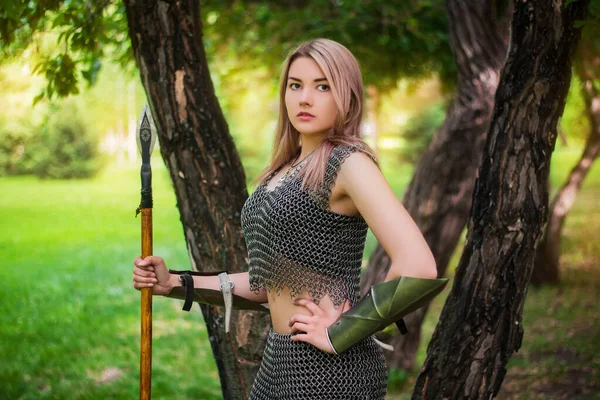 鎖状の鎧を着た若い中世の女性戦士の肖像で 森の背景に槍を手にしている — ストック写真