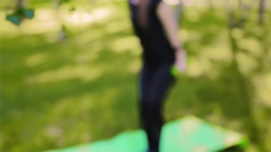 Dambıllarla egzersiz yapan bokeh 'ten ince, atletik kadına odaklanın. Yaz parkında spor.