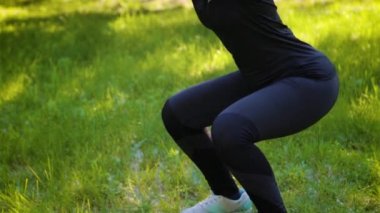 Kamera baştan aşağı hareket ediyor. Spor üniforması giymiş genç ve çekici bir kadın. Parktaki spor aktiviteleri. Sağlıklı yaşam tarzı kavramı.