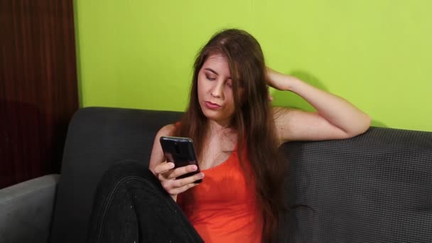 Uma Garota Entediada Senta Sofá Olha Para Smartphone Folheando Páginas — Vídeo de Stock