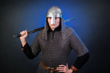 Viking döneminin ortaçağ savaşçısının portresi ve Haçlı Seferleri 'nin başlangıcı. Zincirli zırhlı ve miğferli şövalye koyu siyah ve mavi arka planda izole edilmiş bir kılıçla donatılmış..