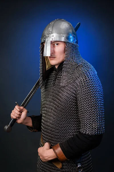 Viking döneminin ortaçağ savaşçısının portresi ve Haçlı Seferleri 'nin başlangıcı. Zincirli zırhlı ve miğferli şövalye koyu siyah ve mavi arka planda izole edilmiş bir kılıçla donatılmış..
