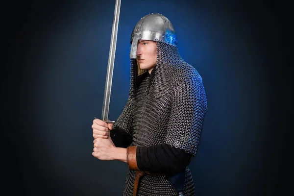 维京时代晚期和十字军东征开始的中世纪战士的画像 戴着锁链的骑士 戴着头盔 带着一把剑 隔离在黑暗 黑色和蓝色的背景下 — 图库照片