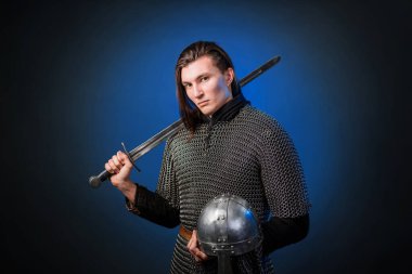 Viking döneminin ortaçağ savaşçısının portresi ve Haçlı Seferleri 'nin başlangıcı. Zincirli uzun saçlı şövalye, siyah ve mavi arka planda izole edilmiş bir kılıçla donatılmış..
