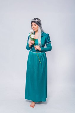 Orta çağ, fantezi, turkuaz bir elbise ve gümüş bir taç giymiş beyaz güllerle poz vermiş, beyaz bir arka planda izole edilmiş bir prenses portresi..