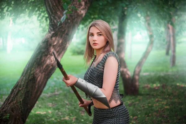 暗い森を背景に槍を手に鎖状の鎧を着た若い中世の女性戦士の肖像画 — ストック写真