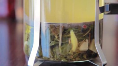 Dipteki hareketler, Fransız pres makinesinin yakın çekimi, bitki çayı demleme. Basın yükselir ve düşer, otlar yüzer.