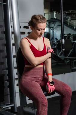 Spor salonundaki egzersiz makinesinde poz veren genç ve güzel bir kadın..