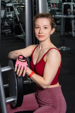 Spor salonundaki egzersiz makinesinde poz veren genç ve güzel bir kadın..