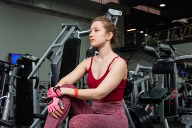 Spor salonundaki egzersiz makinesinde egzersiz makinelerinin arka planında poz veren genç atletik çekici kadın..