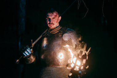 Zırhlı bir şövalye, elinde kılıç ve meşale, kasvetli bir gece ormanında yürüyor. Ortaçağ savaşçısı, kanlı ve yaralı, karanlıkta avlanır ve arar..