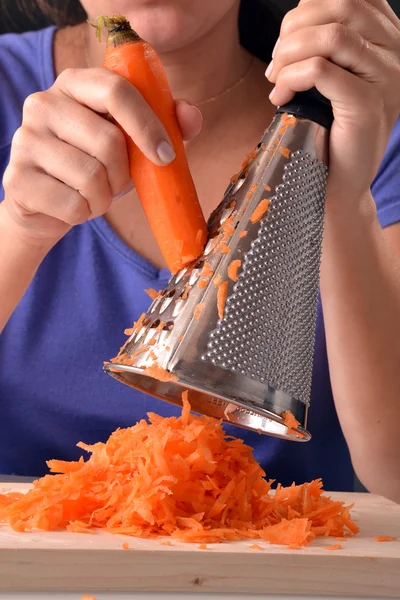 Frau raspelt Möhre. — Stockfoto