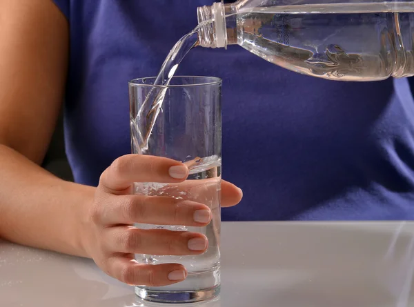 Vrouw gieten van water in een glas. — Stockfoto