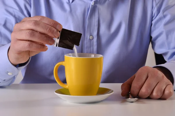 Hombre poniendo azúcar en la taza de café — Foto de Stock