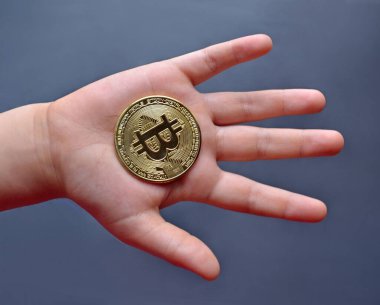 Çocuk elinde bir bitcoin kripto para jetonu tutuyor.