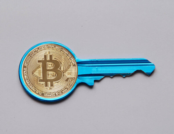 Bitcoin token on key concept isolated on grey background.