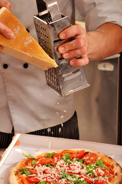 Cozinhe adicionando queijo na pizza — Fotografia de Stock