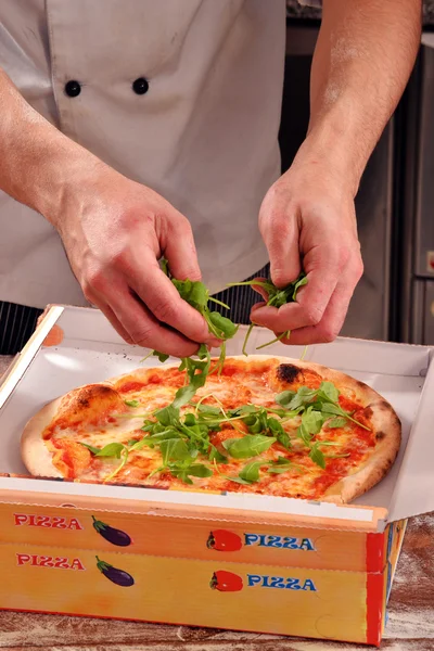 Cuire en ajoutant de la ruccola sur la pizza — Photo