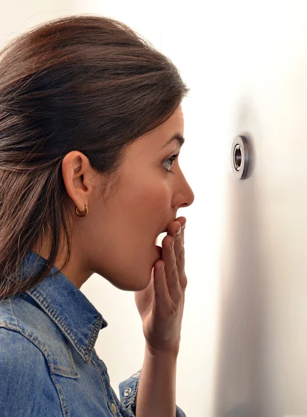 Woman looking out through peephole — Stock Photo, Image