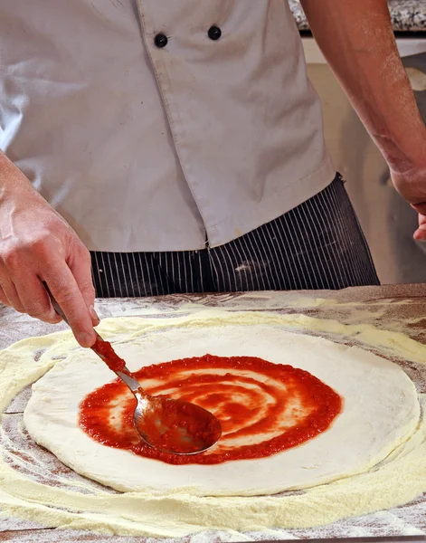 Cozinheiro adicionando molho de tomate — Fotografia de Stock