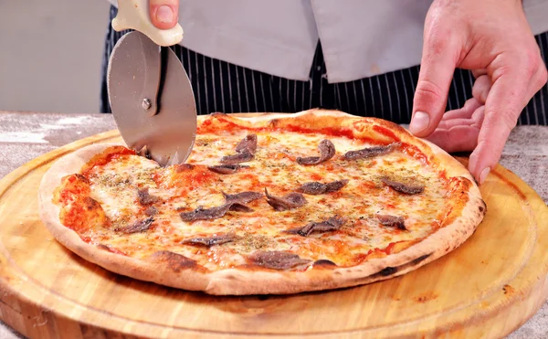 Snijden ansjovis pizza — Stockfoto
