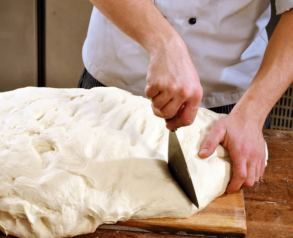 Cook preparing and cutting bread — Stock Photo, Image