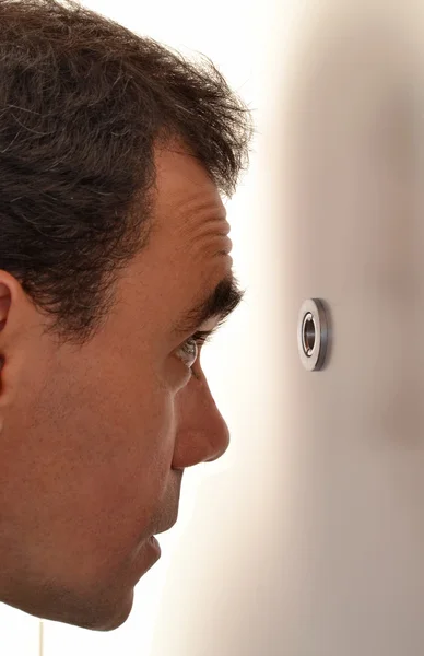 Man looking out through peephole — Stock Photo, Image