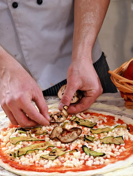 Homem adicionando ingredientes na pizza . — Fotografia de Stock