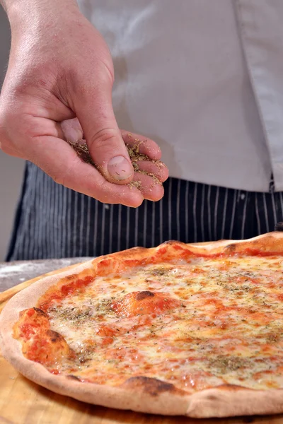 Homem chovendo especiarias em pizza . — Fotografia de Stock