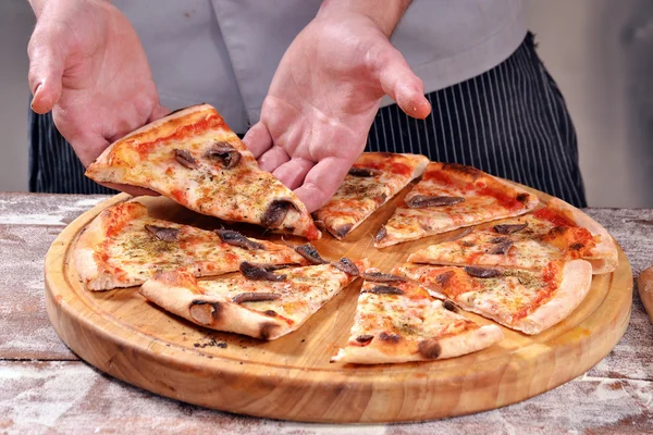 Cozinhe segurando uma fatia de pizza . — Fotografia de Stock