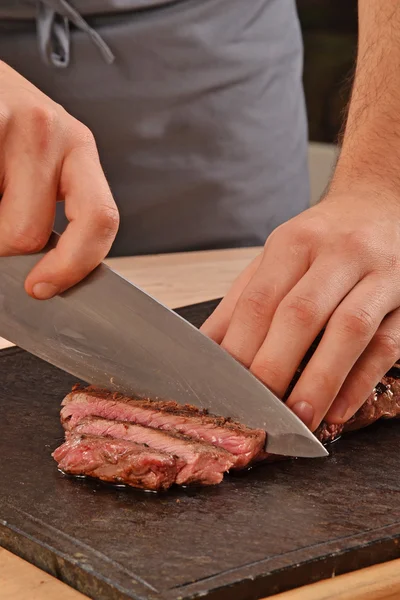 Cook slicing grilled beef — Stockfoto