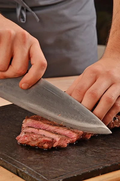 Cook slicing grilled beef — Stockfoto