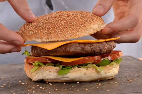 Руки держат и готовят гамбургер . — стоковое фото