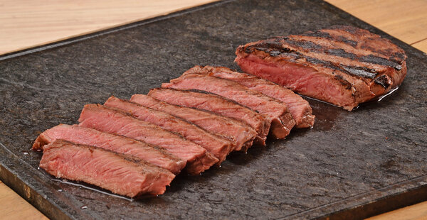 Sliced grilled beef steak on stone board