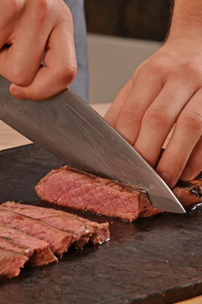 Cook slicing grilled beef — ストック写真